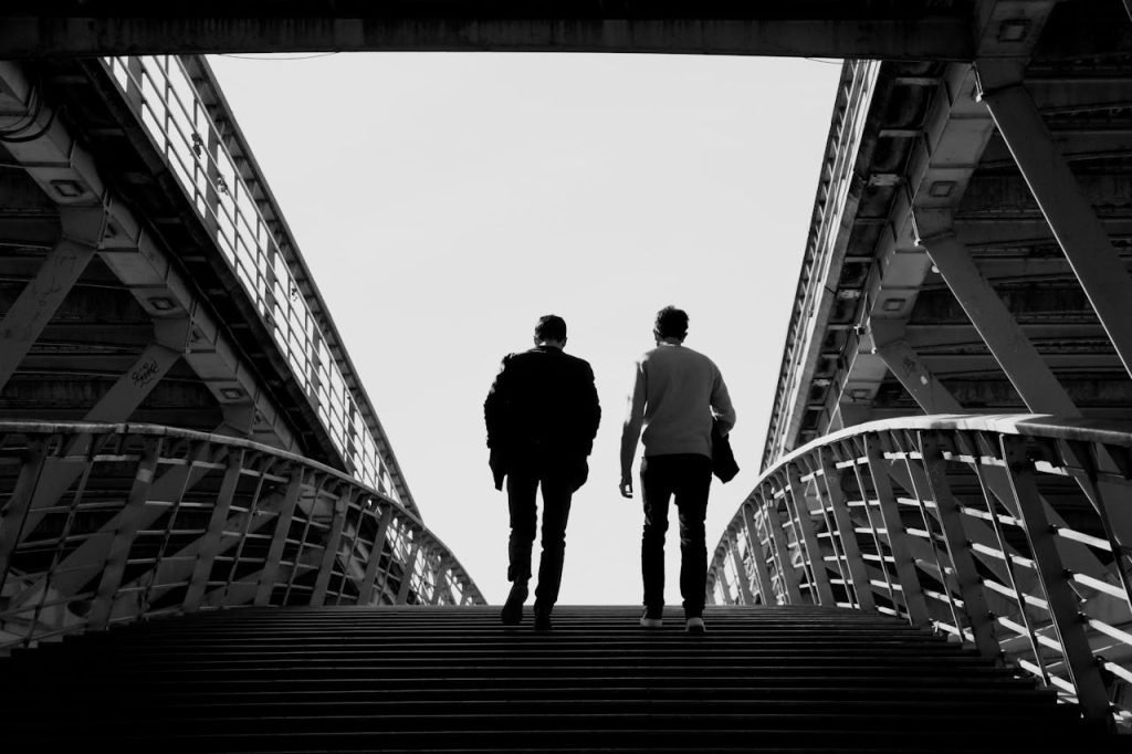 Two people walking across a modern bridge, showcasing urban architecture.